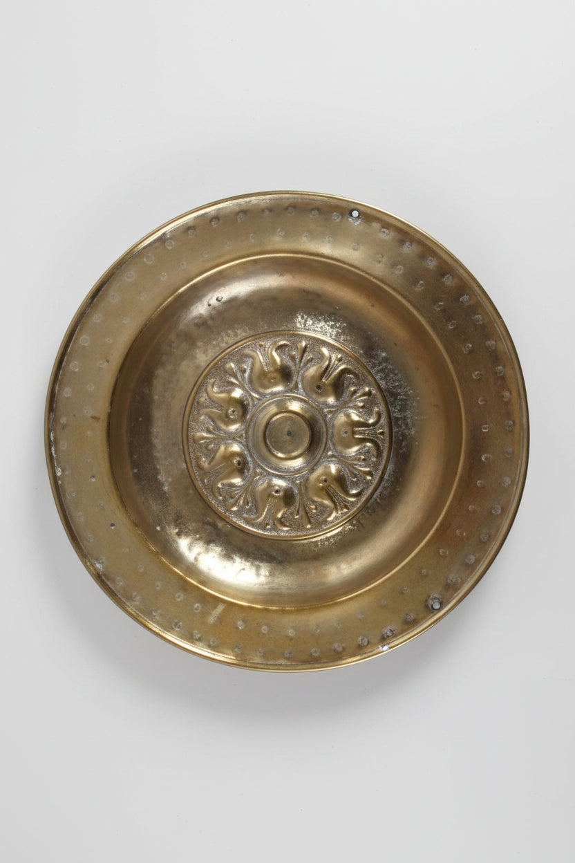 Brass decorative plate with intricate design on a white background