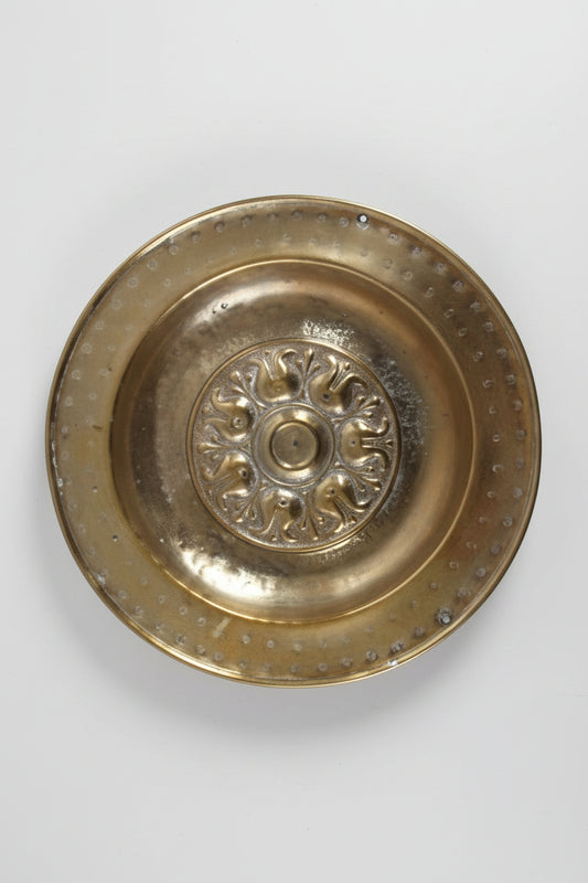 Brass decorative plate with intricate design on a white background