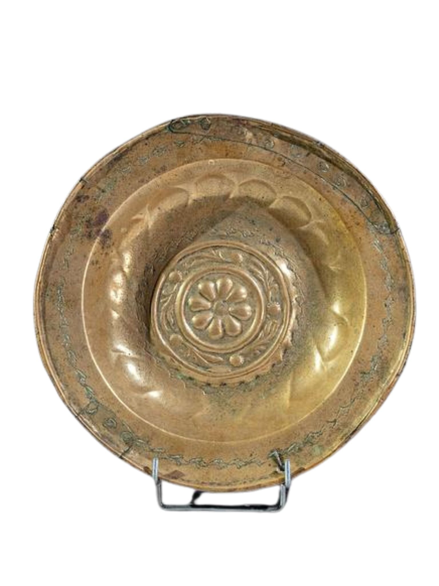 Antique brass plate with a central floral or geometric motif, displayed on a stand.