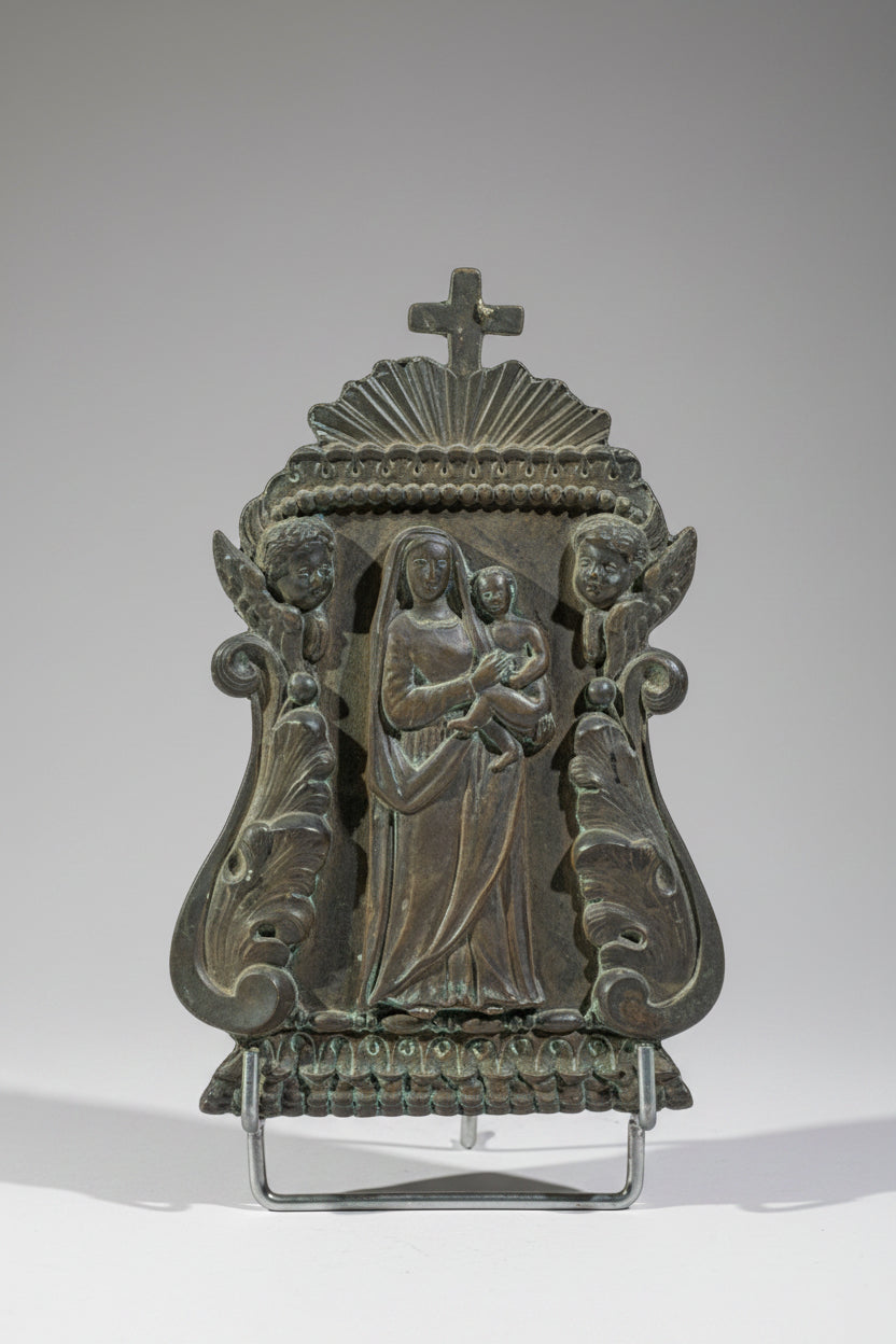 A silver-plated bronze kiss of peace sculpture with the effigy of the Virgin and Child, surrounded by cherubs' heads.
